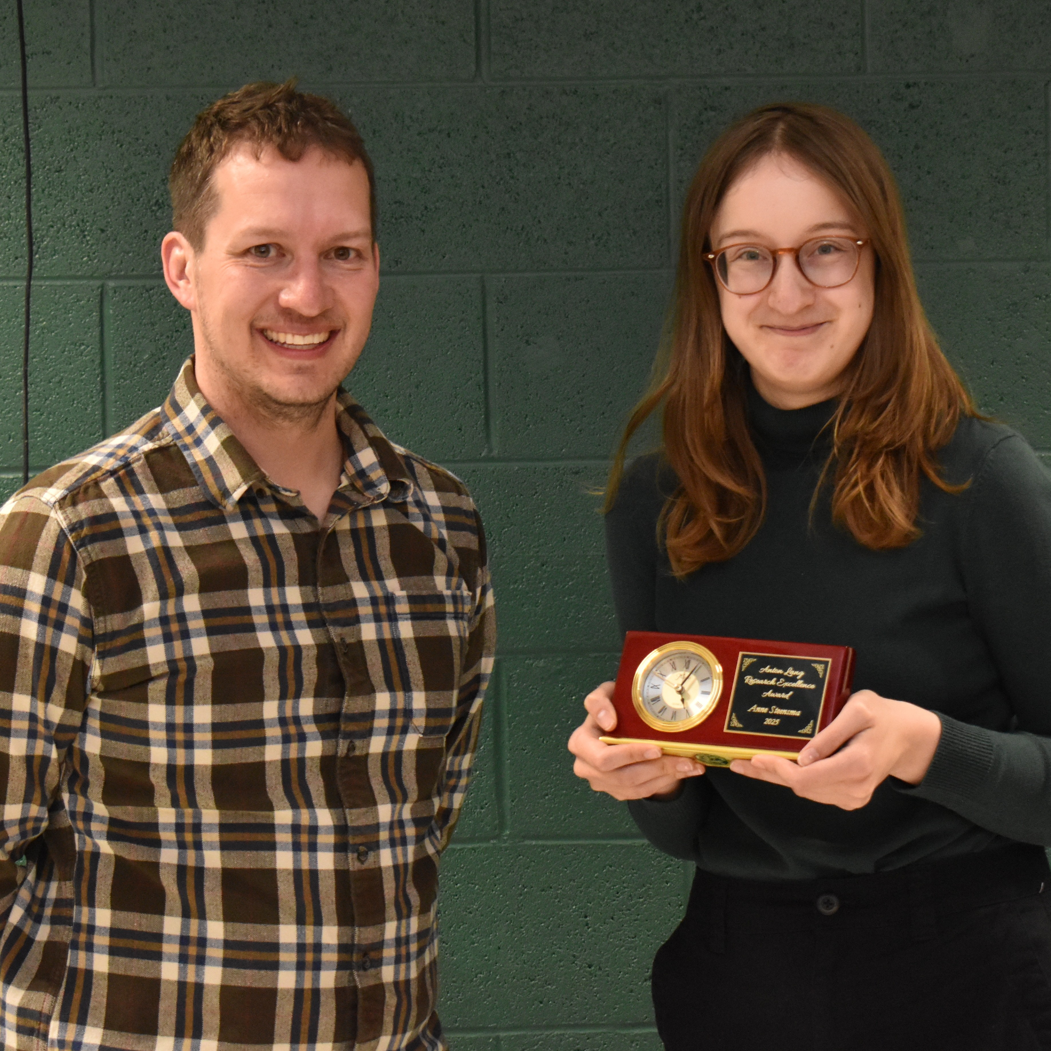 Two people, one holds an award